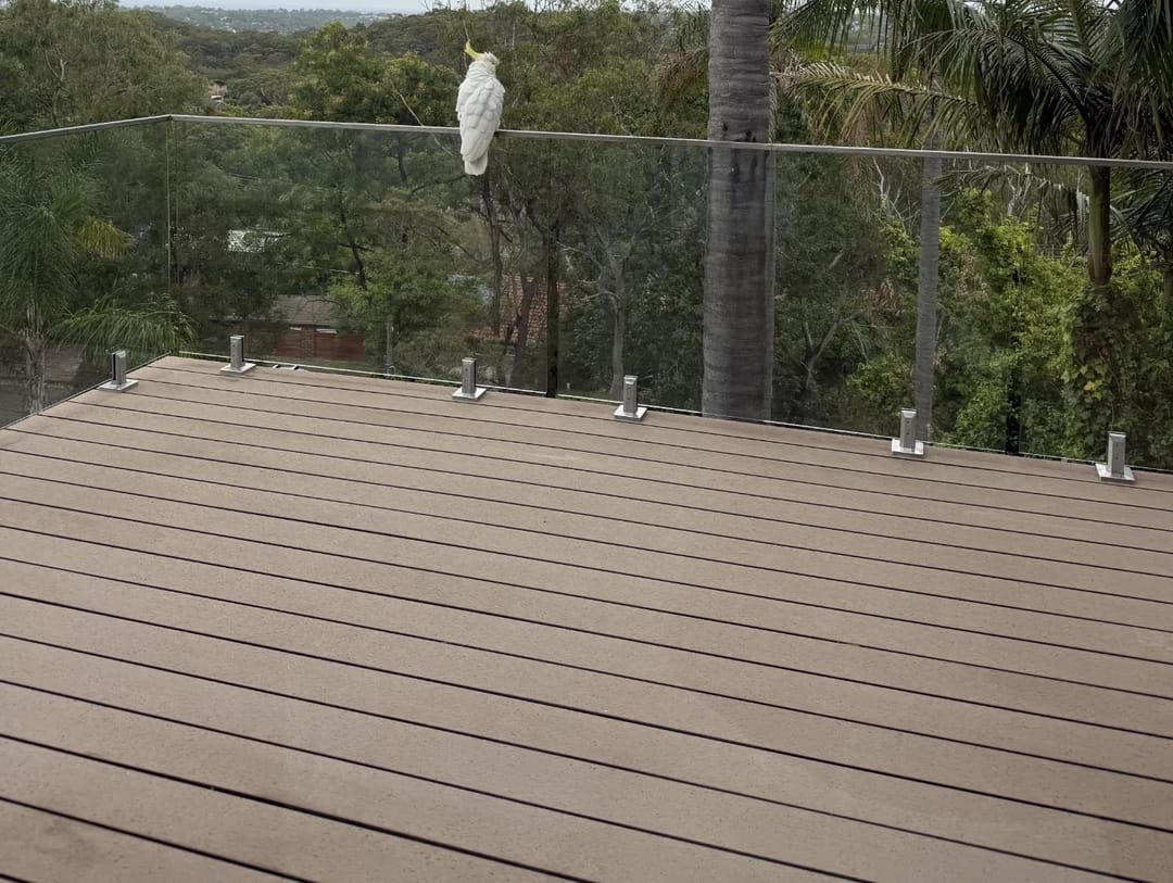 Elevated deck in CleverDeck Original Weathered Stone with a frameless glass balustrade overlooking trees
