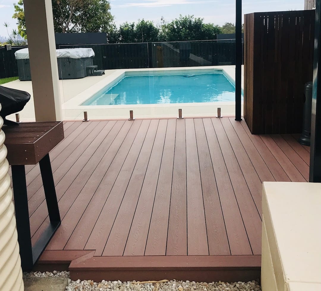 Sun Decking Classic Chocolate deck beside a pool with glass fencing, a covered outdoor area and screened side wall