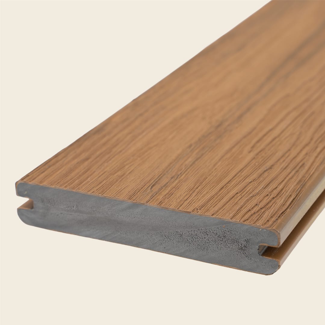 WoodEvo ADVANCED grooved PVC decking board in Oak, a warm honey-brown with embossed grain, shown end-on