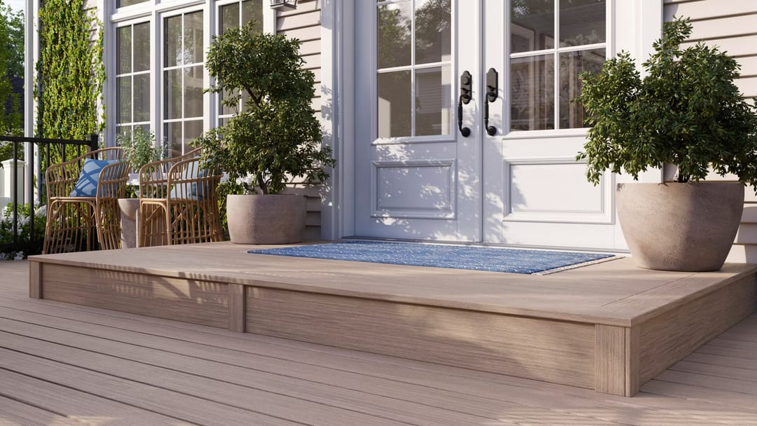 Computer-rendered low Malted Barley deck platform outside white French doors with a blue rug and two potted topiaries