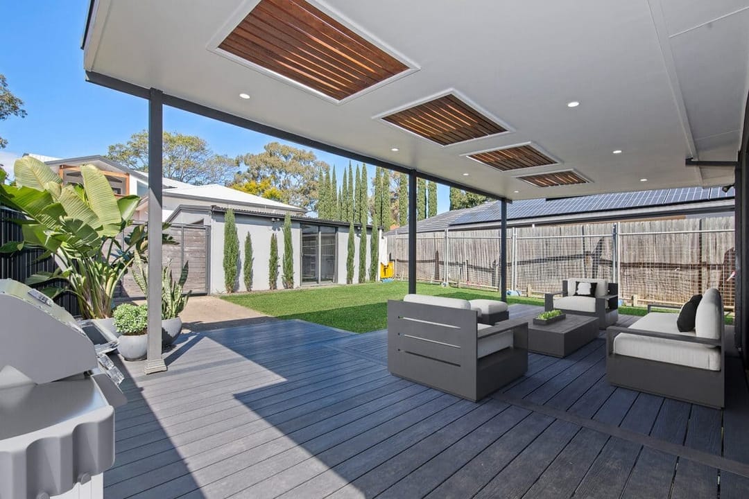 Covered alfresco deck in dark Brite HD PRO Slate Grey with grey outdoor lounges and a lawn in a Concord West backyard