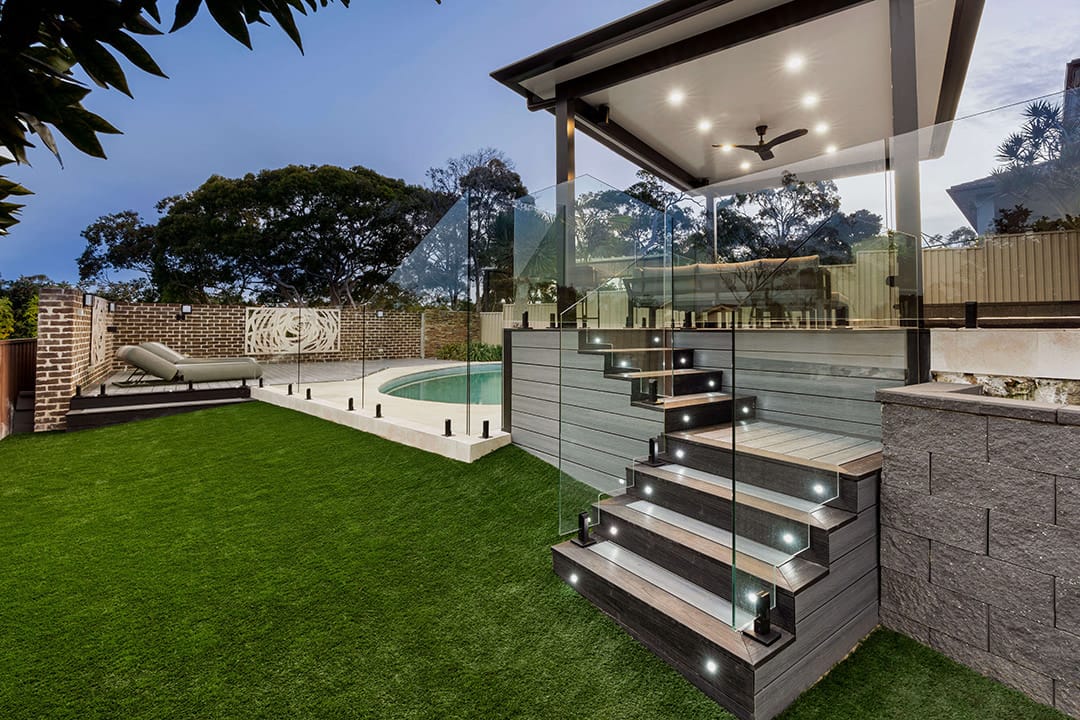 Brite HD PRO Light Grey decked steps lit at dusk, leading down from a covered alfresco to a lawn and glass-fenced pool in Illawong